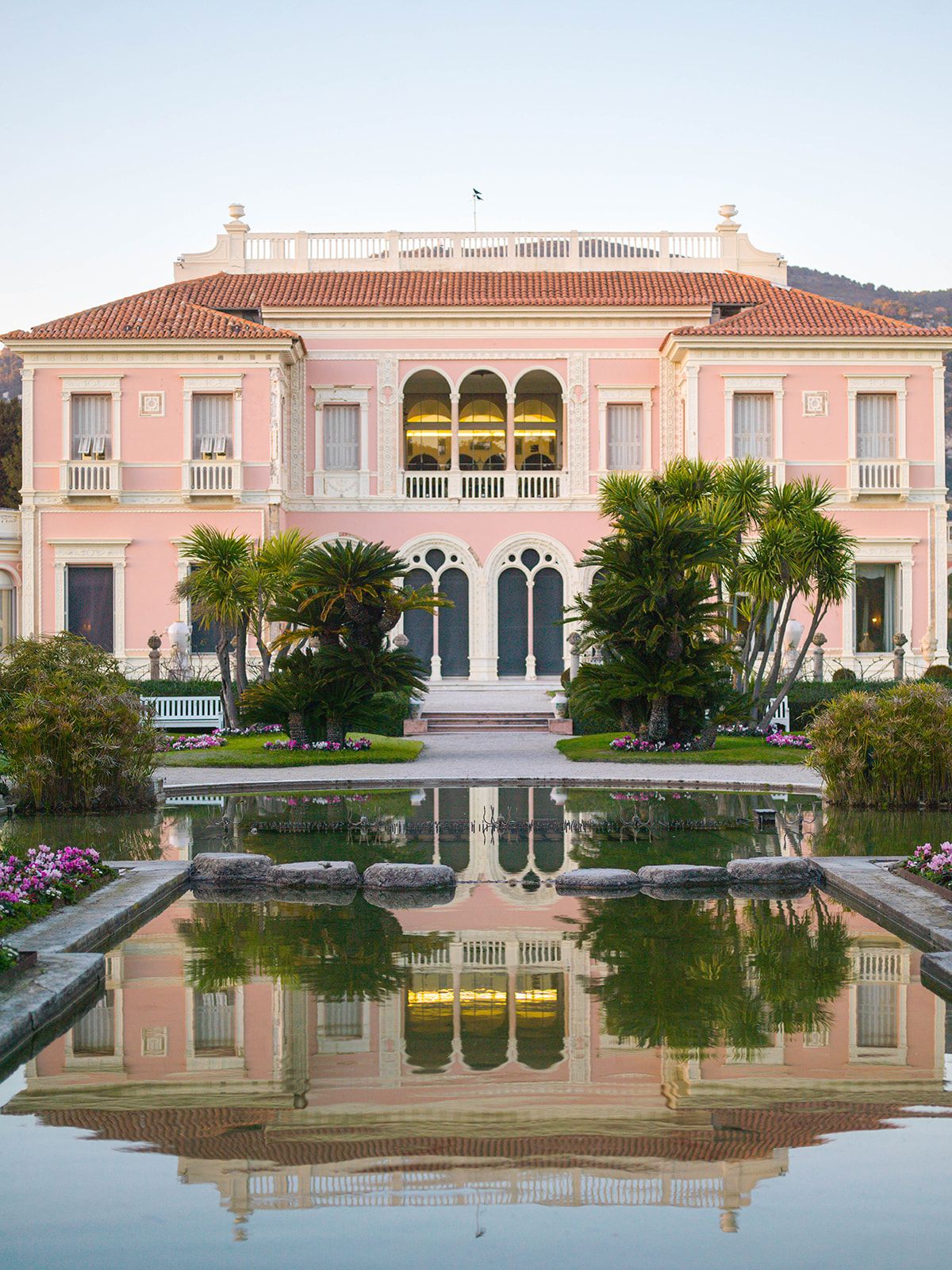 Close view of the pink villa reflected in the French garden pool